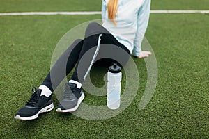 Girl after exercise, drinking water on the football field. Portrait of beautiful girl in sportswear.