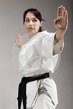 Girl exercising karate, posing against gray background