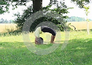 Girl exercising yoga on meadow