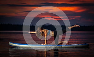 Girl exercising yoga on paddleboard in the sunset on scenic lake Velke Darko