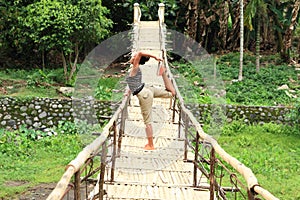 Girl exercising yoga on traditional bridge over river photo