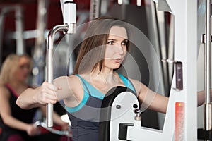 Girl exhales while doing exercises with weights on training apparatus