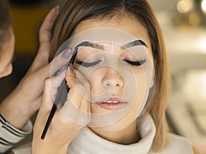 Girl on a eyebrow correction procedure. Eyebrow tinting with brush