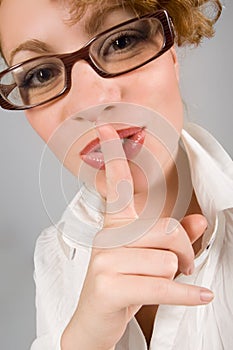 Girl with eyeglasses with finger near lips