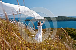 Girl with fabric in hands in the wind