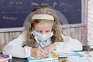 Girl with face mask, back at school after covid-19 quarantine and lockdown. School girl writing in exercise book. Child