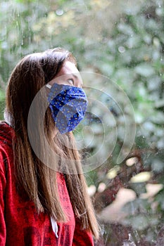 Girl with face mask looking out of window