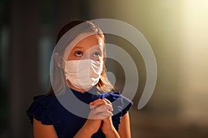 Girl in face mask praying for coronavirus victim