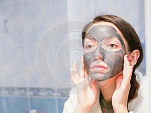 Girl and face mask. Woman with clay carbo black mask on her face. The girl takes care of oily skin. Cosmetic procedures. Skin care