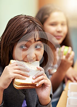 Girl, face and student biting sandwich for meal, break or snack time in classroom at school. Hungry young kid or