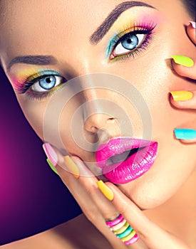 Girl face with vivid makeup and colorful nail polish