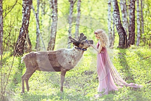 Girl in fairy dress and reindeer in the forest