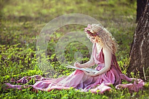 Girl in a fairy dress sitting under a tree in the woods