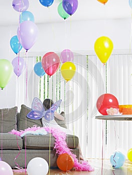 Girl In Fairy Wings With Balloons On Sofa