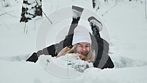 A girl falls on the snow in winter in the forest.