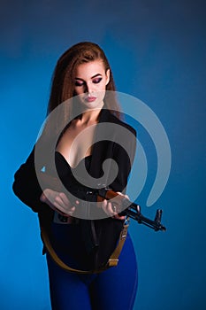 Girl fashion photography in the studio with a gun is dangerous