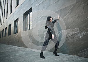 Girl in fashionable black casual clothes on background of stone wall, modern urban architecture, vogue style photo