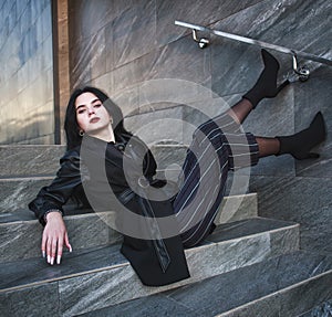 Girl in fashionable black casual clothes on background of stone wall, modern urban architecture, vogue style photo