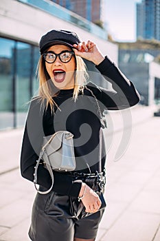 Girl in fashionable clothes, with a bag. Young beautiful model girl smiling and holding a hat hand. emotional surprised. open