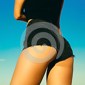 Girl in fashionable Jeans Shorts outdor, on background sky