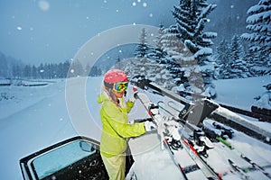 Girl fastening skis on car roof in the evening photo