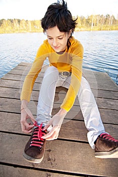 Girl fastens laces on gym shoes