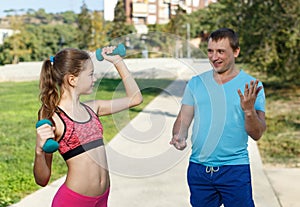 Girl with father exercising with dumbbells