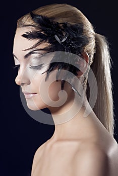 Girl with feathered accessory, she looks down