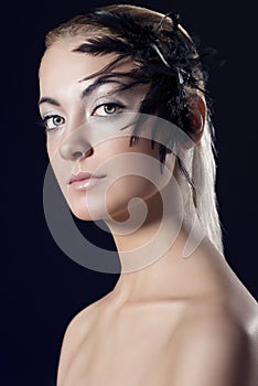 Girl with feathered accessory and serious expression