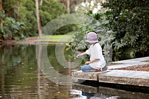 Girl feeding fish in a garden pool