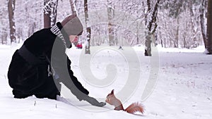 Girl feeds the squirrel nuts in the park.