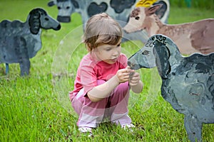 The girl feeds wooden sheep photo