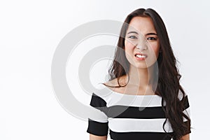 Girl feeling pity or sorry for friend got in trouble. Attractive awkward young asian woman standing embarrassed or upset photo