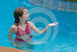 Girl feeling rain drops while in a swimming pool