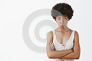 Girl feeling upset and disappointed after losing cometition, standing silly and gloomy with sad expression over gray