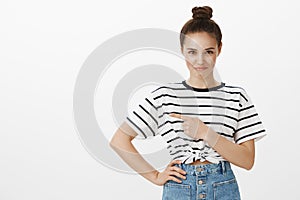 Girl feels shy showing her new artwork to teacher. Portrait of insecure good-looking feminine woman with bun hairstyle