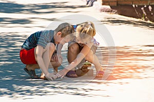 The girl feels sorry for the boy, her brother, who was injured while riding a skateboard on a road in the street