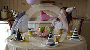 A girl in a festive cap and a medical mask sits at the table alone on her birthday. Depression from lack of friends. Coronavirus