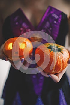 A girl in a festive dress holding pumpkins for Halloween