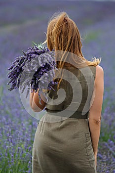 Girl in a field of lavender flowers with a bouquet in her hands