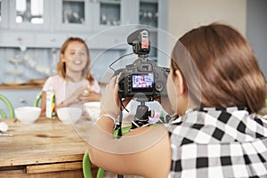 Girl filming her friend for cookery video blog in kitchen photo