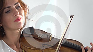 Girl fingering the strings playing the violin. Close up. White background