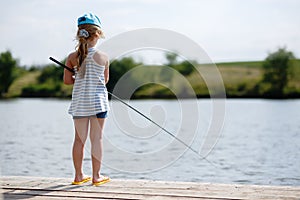 Girl fishing from a dock on a lake or pond.