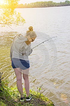 Girl with fishing rod fishing in the pond