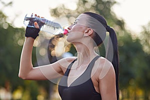 Girl fitness athlete drinking water after workouts