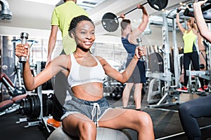 Girl in fitness gym exercising her shoulder on machine