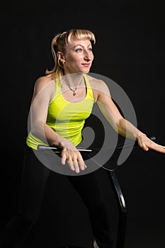 Girl on a fitness trampoline on a black background in a yellow t-shirt black fit sport, activity lifestyle vitality