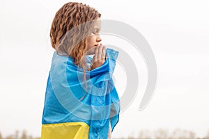 Girl with the flag of Ukraine prays for the victory