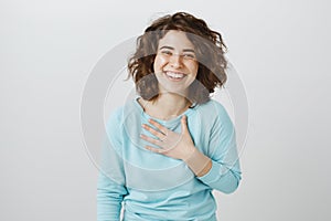 Girl is flatter to bottom of heart. Studio shot of pleased and thankful beautiful caucasian female, holding palm on