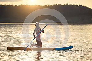 Girl floating on supboard on a river or lake.